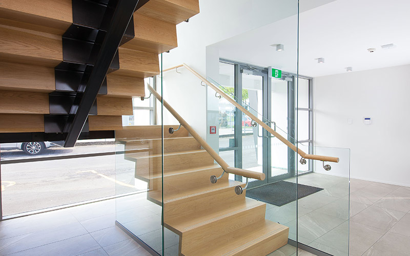 Commercial stairs with central steel stringer and American Oak treads and risers. Raised stainless steel strips create a non-slip nosing.