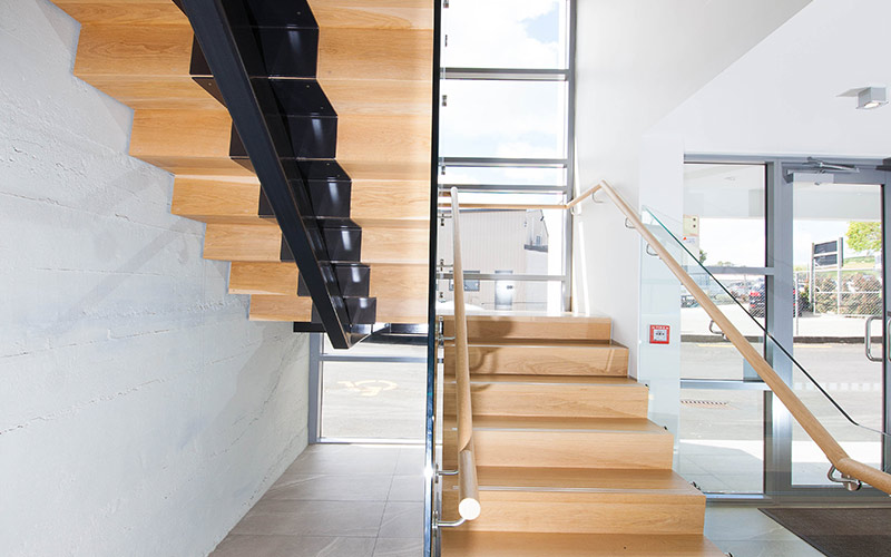 Commercial stairs with central steel stringer and American Oak treads and risers. Raised stainless steel strips create a non-slip nosing.
